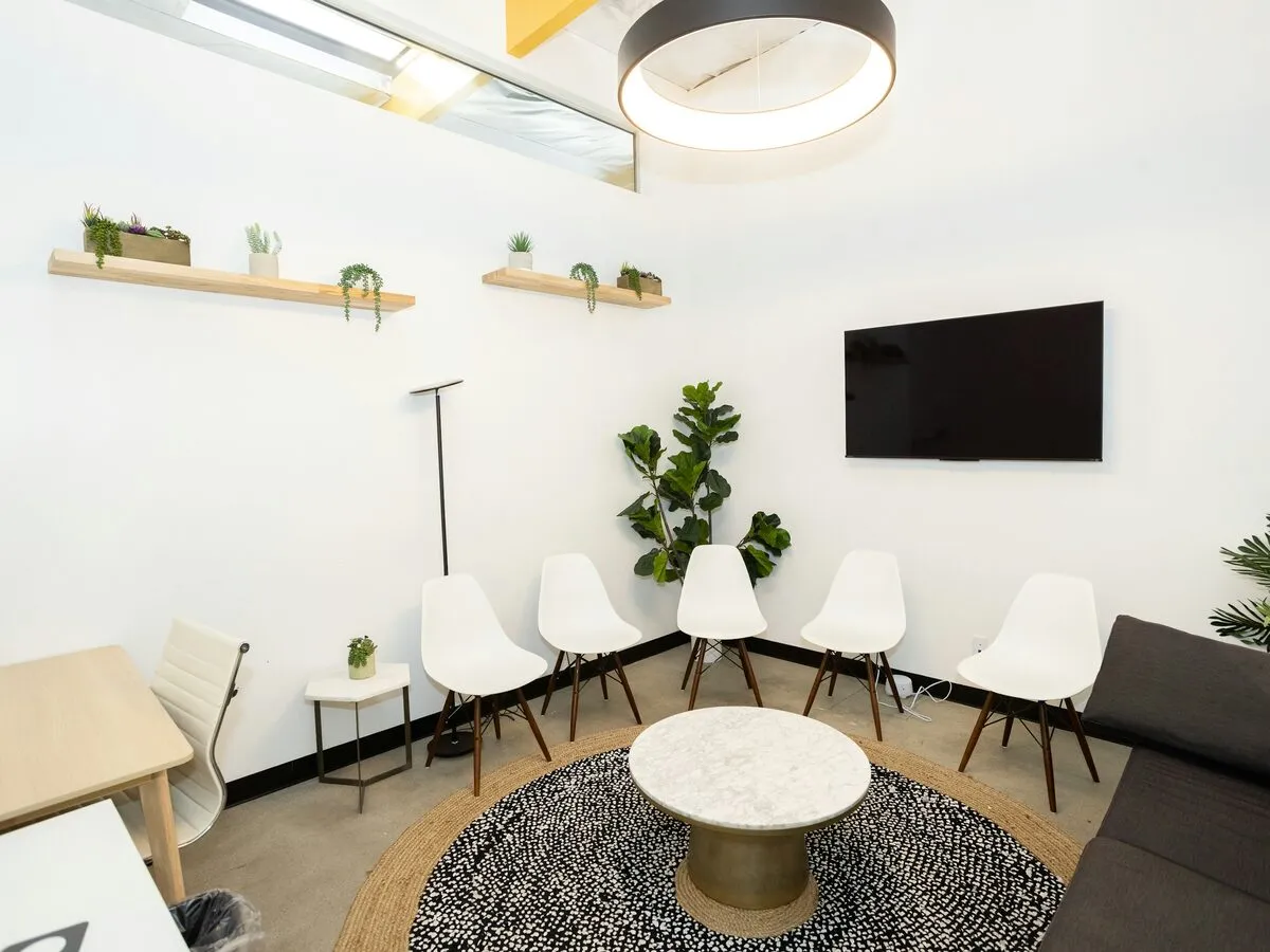 Waiting area with white chairs, plants and a round coffee table