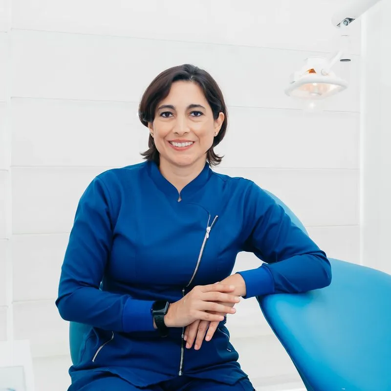 Dr Priya Shah, principal dentist, in navy scrubs beside a treatment chair